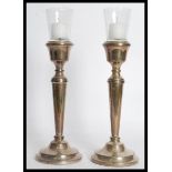 A pair of 20th century silver hallmarked candlesticks having inset glass sconces atop. Raised on