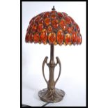 A vintage 20th century Art Nouveau style bronzed table lamp having a pressed circular base with