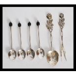 A group of four hallmarked silver coffee bean spoons along with a set pair of pickle fork and