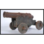 A vintage 20th century large cast iron floor cannon having wooden mounts. Measures 28 cm high, 38 cm