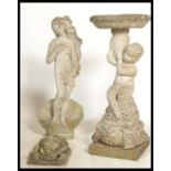 A group of vintage stone garden features to include a statue of a maiden stood on a open clam
