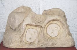 An abstract carved Bath stone sculpture of many stylised faces within a rock formation.
