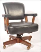 A 1950's retro vintage office desk chair having a thick stuffed black leather seat , backrest and
