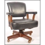 A 1950's retro vintage office desk chair having a thick stuffed black leather seat , backrest and