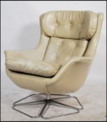 Vono - A 1970's retro cream faux leather swivel chair raised on a sectional chrome metal tubular