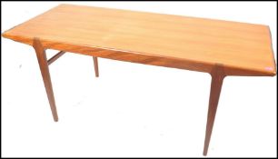 A 1970's Danish inspired teak wood dining table being raised on turned and tapering legs with a