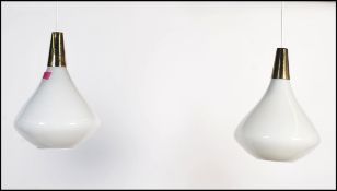 A pair of 20th Century retro vintage white glass and brass pendant lights in the teardrop form in