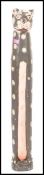 A fantastic wooden carved totem of an abstract cat painted in black, white and pink standing.
