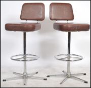 A pair of 20th Century bar stools having a chromed stand and quadruped base with footrest supporting