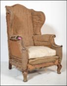 A 19th century large concave fronted oversized wingback armchair. Raised on stub mahogany legs,