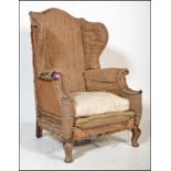 A 19th century large concave fronted oversized wingback armchair. Raised on stub mahogany legs,