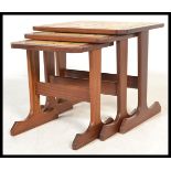 A retro 20th Century G - Plan teak wood tiled top nest of tables raised on shaped supports. Measures