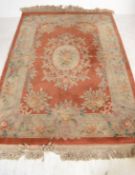 A 20th century Chinese wool rug of large proportions having red ground, floral decoration with