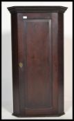 A George III 19th century oak tall hanging corner cupboard. Flared cornice over full length door