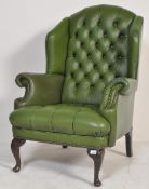 A 20th century Chesterfield green leather wing back armchair having a button back rest and cushion