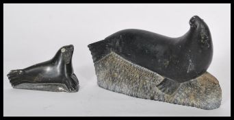 An early 20th century Inuit Eskimo soapstone carved figurine of a large seal on rock base. Signed by