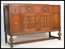 A 1920's Art Deco oak sideboard dresser raised on cup and cover supports united by stretchers having
