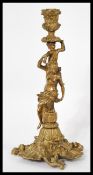 A 19th century large heavy French bronze candlestick raised on a scrolled base with figural cherub
