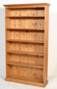 A tall antique style pine bookcase cabinet being raised on plinth base with a series of shelves