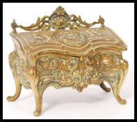 A 19th century brass desk inkwell modelled as a French commode decorated in relief with scroll