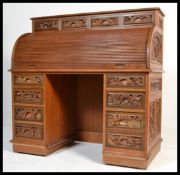 A 20th century Chinese tambour fronted roll top desk having multiple carved panels raised on twin