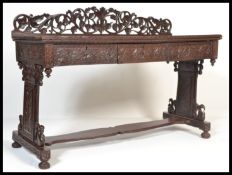 A 19th century Indian anglo colonial hardwood large hall table with three carved drawers on a carved