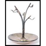 A silver hallmarked ring stand having a slopped bowl with naturalistic leaf branch to centre.