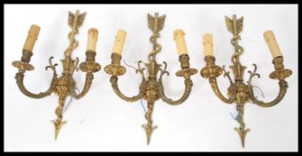A set of three classical styled brass wall lights having arrow motif to centre.