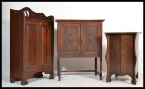 A 1920's Arts & Crafts oak freestanding cabinet with pierced gallery top over cupboard together with