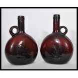 A pair of 19th century Dutch amber glass wine flask bottles having moon flask shaped bodies with