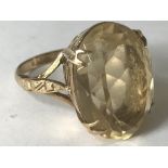 A hallmarked 9ct gold ring having a large central faceted citrine stone set in open gallery