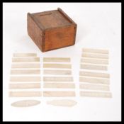 A collection of 19th century mother of pearl board gaming pieces counters held within a wooden
