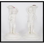A pair of 19th century ceramic table taper candlesticks in the form of cherubs holding cornucopia