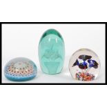 A group of glass paperweights to include a 19th century Nailsea glass dump paperweight with inset