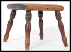 A 19th century Victorian small elm country milking stool raised on turned legs with panel seat.