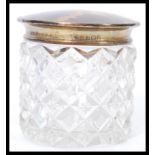 An early 20th century silver hallmarked and blonde tortoiseshell lidded cut glass dressing table pot