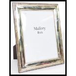 A large silver hallmarked picture photo frame retailed by Mallory Bath having an easel back.