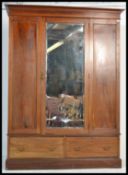 An Edwardian mahogany inlaid triple wardrobe comprising a central mirror door with panelled sides