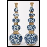 A pair of unusual Chinese blue and white quadruple gourd vases being hand painted with lotus