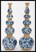 A pair of unusual Chinese blue and white quadruple gourd vases being hand painted with lotus