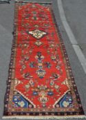 A Persian Islamic red ground carpet floor runner featuring geometric decorative patterning in the