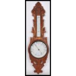 An early 20th century - 1930's milk glass facia oak wall barometer of banjo form having