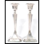 A matched pair of silver hallmarked candlesticks raised on square bases with tapering columns and