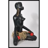 A vintage 20th century carved ebony figurine of a nude African lady in tribal attire on her knees