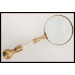 A 20th century hand held magnifying glass having a brass handle with inset mother of pearl panels.