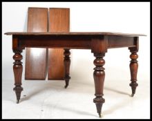 A 19th century Victorian mahogany windout dining table being raised on turned baluster legs with