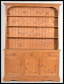 An antique style pine Welsh dresser being raised on a plinth base with a series of cupboards and
