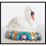 A Royal Crown Derby ceramic paperweight in the form of a nesting swan complete with stopper.