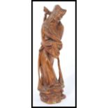 A 19th century Chinese hardwood figurine of a sage elder being hand carved and raised on pedestal