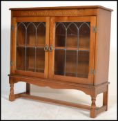 A 20th century lead glass fronted bookcase raised on block and turned legs with twin glazed doors